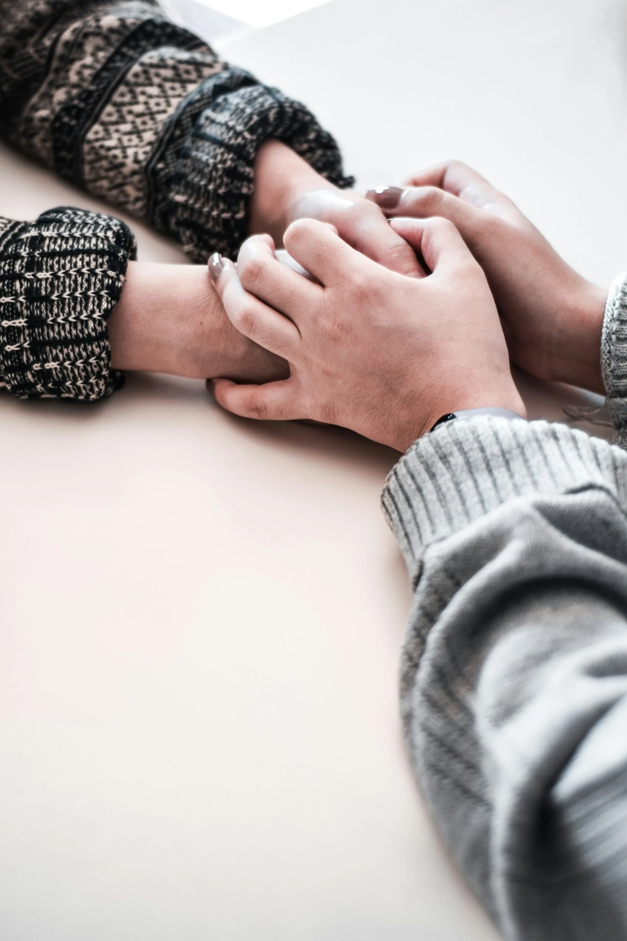 Two people holding hands across a table in a warm, softly lit room